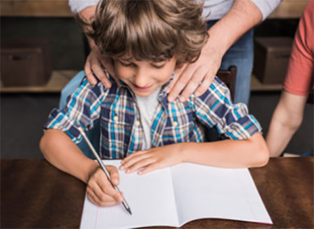 Ребенок пишет в тетради. Сзади стоят родители