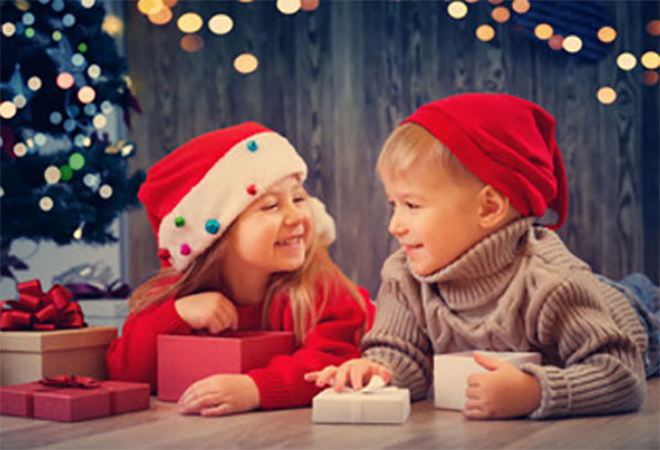 Девочка и мальчик лежат на полу в новогодних шапках