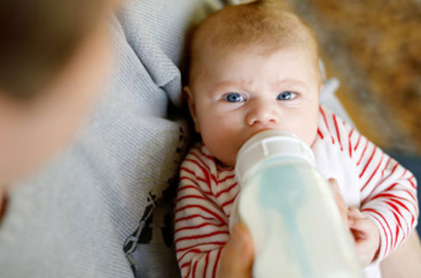 Малыш на руках у мамы пьет с бутылочки