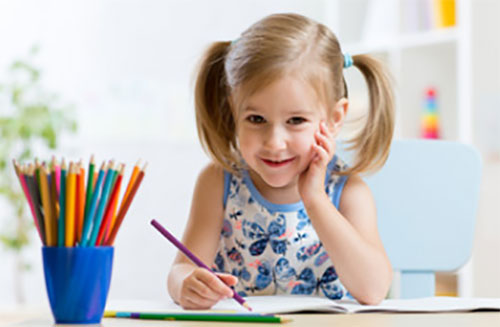 Девочка рисует и улыбается