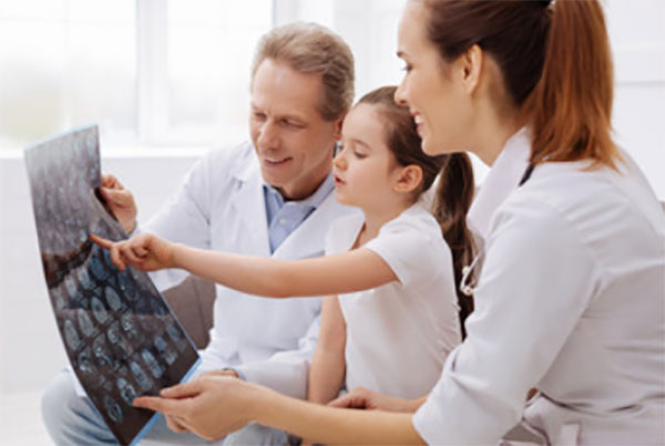 Врачи вместе с ребенком рассматривают снимки МРТ