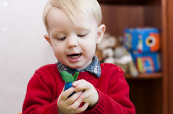 Мальчик с открытым ртом смотрит на слепленную сливу, которую держит в руке