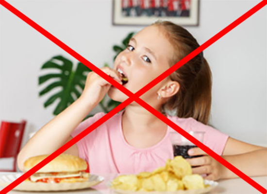 Перед девочкой чипсы, чисбургер, в руках газировка. Изображение перечеркнуто