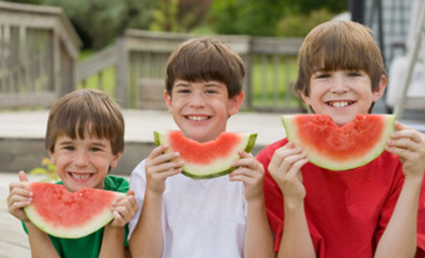 Три мальчика разных возрастов с кусочками арбуза в руках