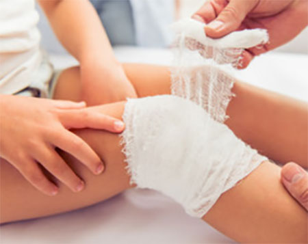 Ребенку забинтовывают колено
