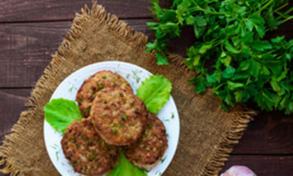 Готовые котлеты с петрушкой на тарелке. Рядом пучок петрушки