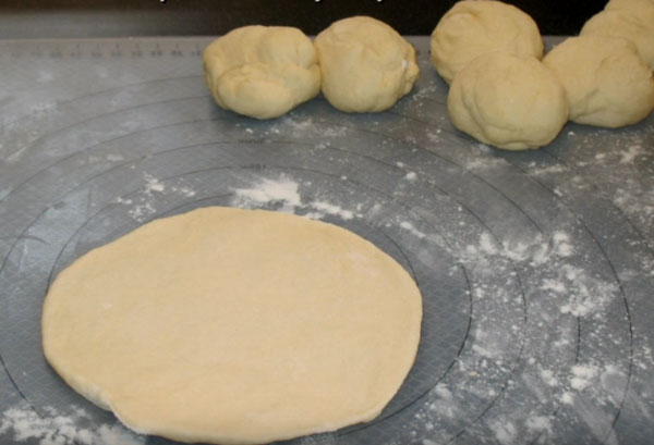 Раскатанная лепешка. На заднем плане шарики теста