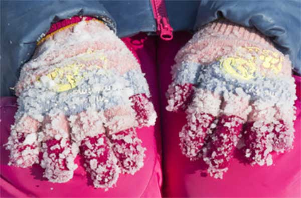 Руки ребенка в перчатках, залепленных в снегу