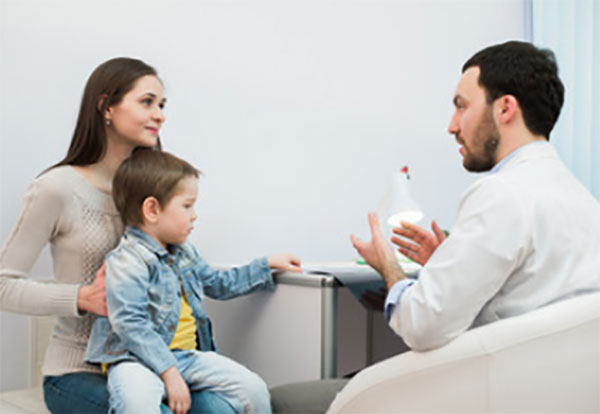 Ребенок сидит у мамы на руках. Доктор что-то объясняет