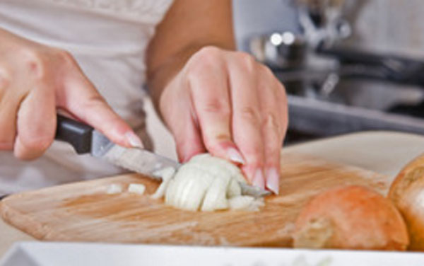 Женщина шинкует лук