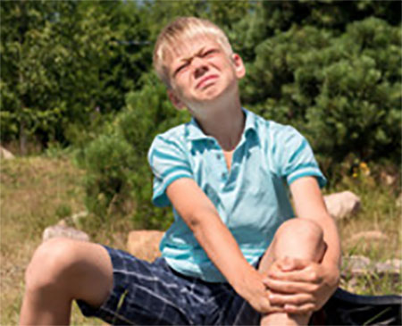 Мальчик держится за ногу, ему очень больно