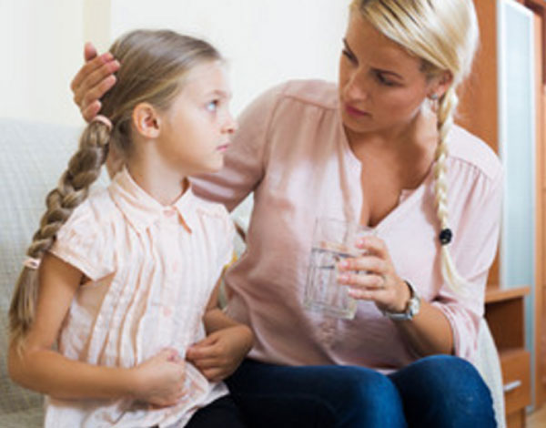Девочка держится за живот. Мама дает ей стакан воды