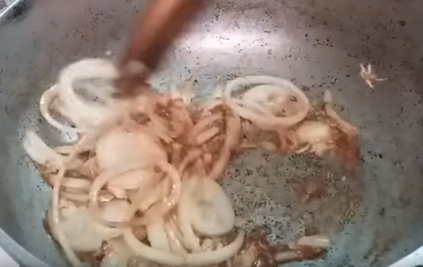 Лук размешивают лопаткой на сковороде