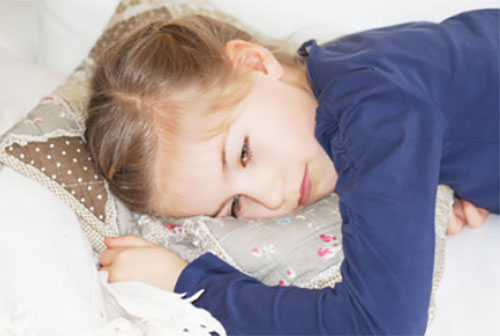 Девочка лежит на подушке. Она явно плохо себя чувствует