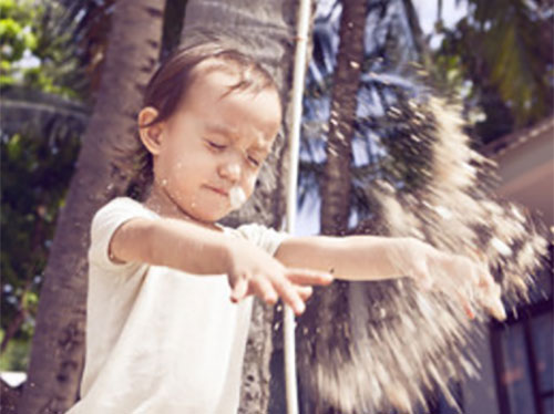 Девочка бросается песком