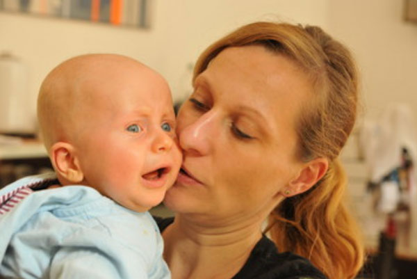 Ребенок без волос плачет у мамы на руках