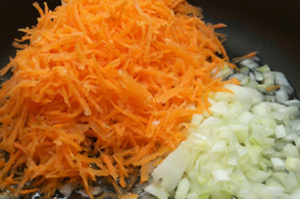 Натертая морковь и покрошенный лук в казанке