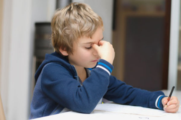 Ослабленный ребенок сидит за столом