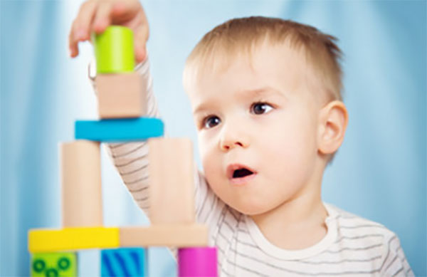 Двухлетний мальчик строит пирамиду из кубиков