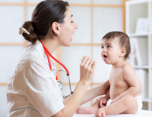 Врач осматривает горлышко маленькому ребенку