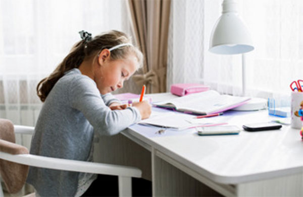 Девочка за столом пишет уроки