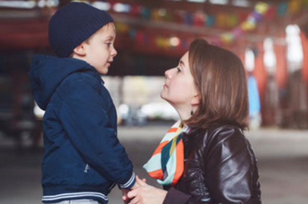 Мама присела на присядки рядом с сыном, пытается что-то ему говорить