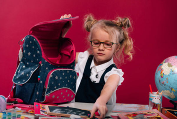 Маленькая девочка в очках собирает портфель