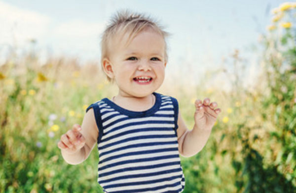 Годовалый ребенок на фоне зелени