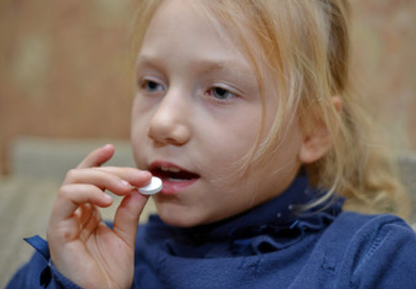 Девочка кладет в рот таблетку