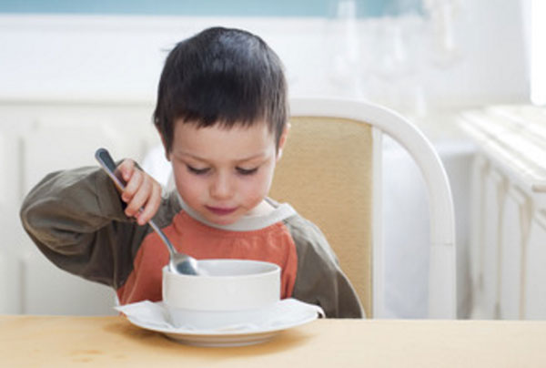 Малыш с недовольным видом водит ложкой по тарелке