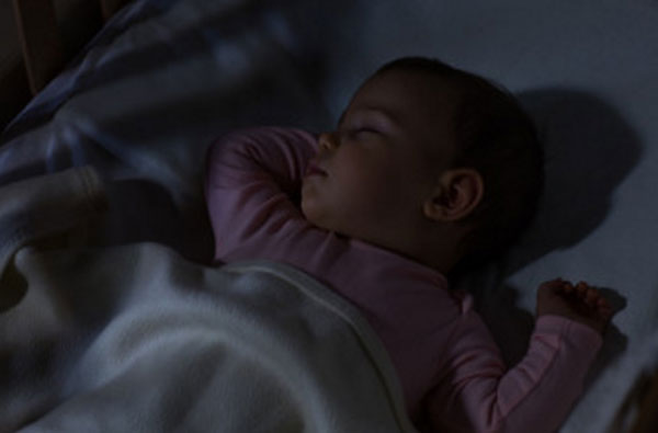 Грудной ребенок спит в темной комнате
