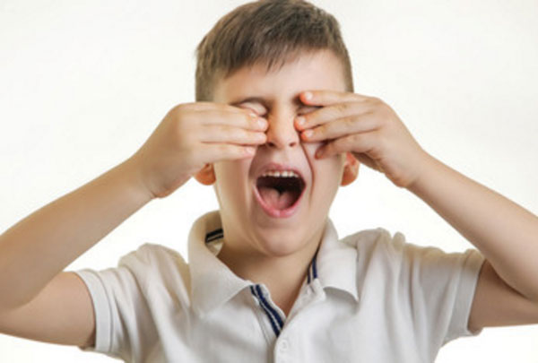 Мальчик трет глаза. Видно, что они у него болят