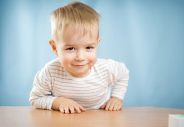 Двухлетний малыш облокачивается на стол