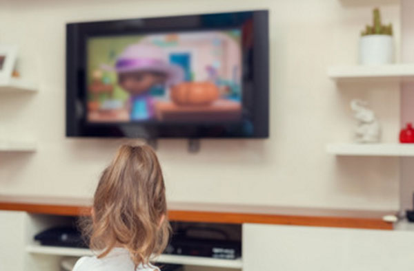 Девочка смотрит мультик по телевизору