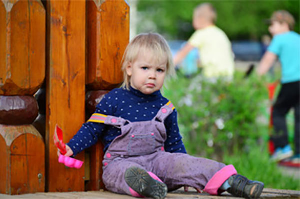 Двухлетняя девочка сидит на земле