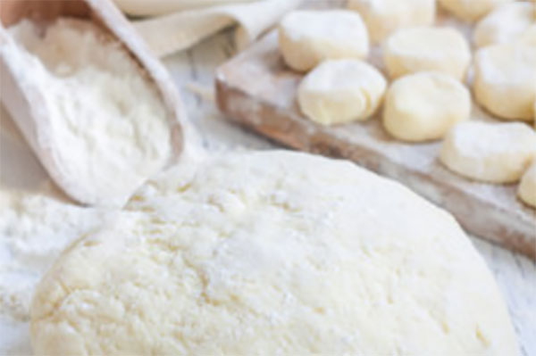 На переднем плане колобок из теста, на заднем нарезанные кусочки теста