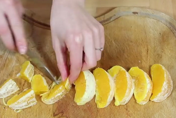 Очищенные дольки апельсина нарезают на кусочки