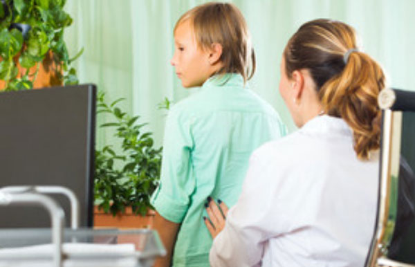 Доктор пальпирует поясничную область ребенка