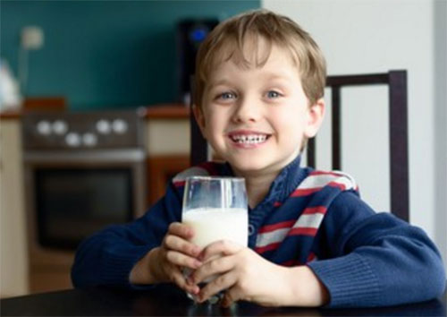 Счастливый мальчик держит в руках стакан с кефиром