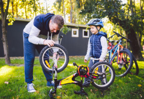 Папа чинит велосипед. Мальчик следит за его работой