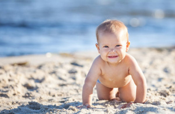 Маленький ребенок ползет по берегу