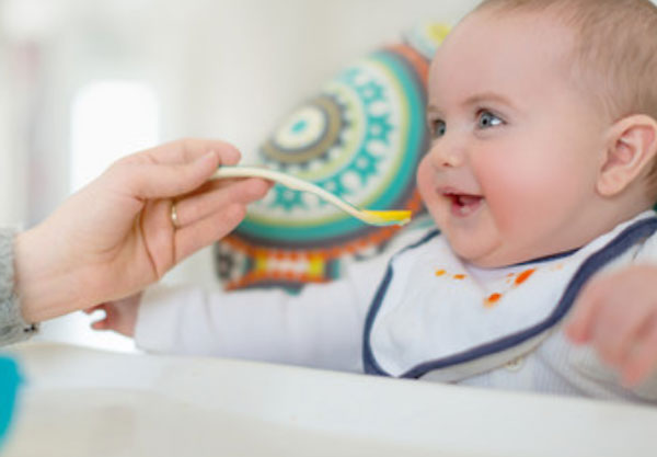 Мама дает сок с ложечки грудному ребенку