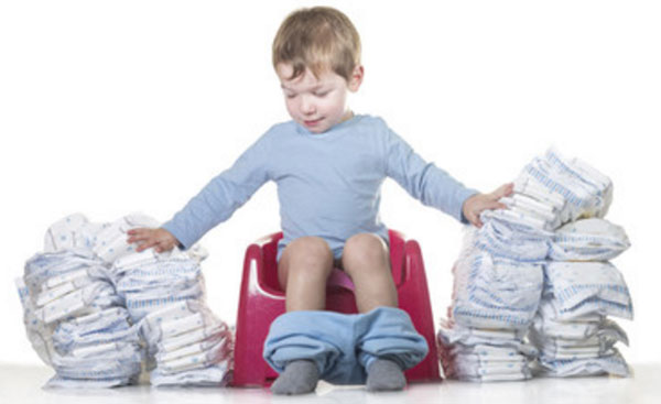 Ребенок сидит на горшочке. По бокам от него стопки подгузников