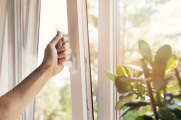 Женщина открывает окно на проветривание