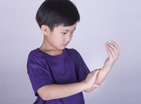 Мальчик трогает свою руку, ощущает боль
