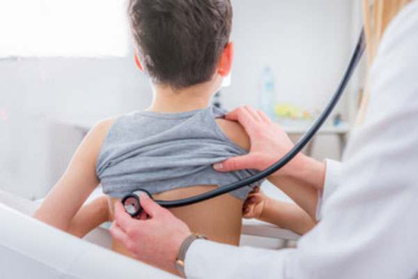 Доктор слушает спину ребенка