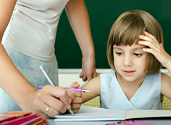 Учитель исправляет девочке в тетради ошибки
