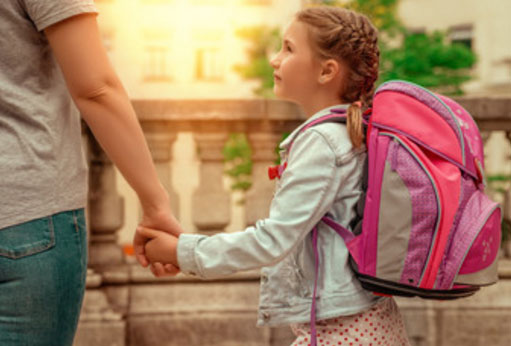 Родитель ведет девочку за руку, у ребенка на спине рюкзак