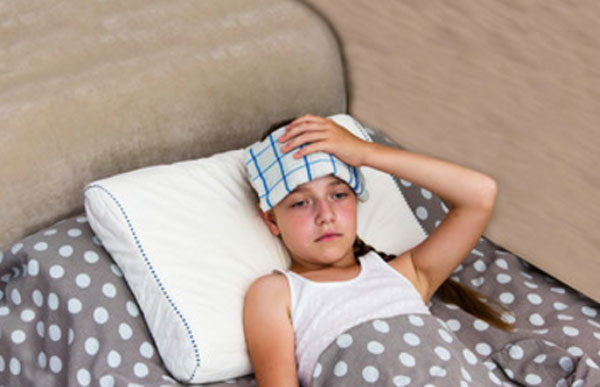 Ребенок лежит в постели. На лбу полотенце, смоченное в воде