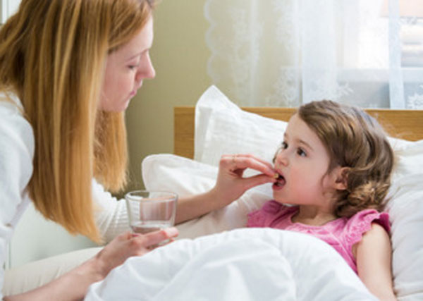 Девочка лежит в кровати. Мама ей дает таблетку